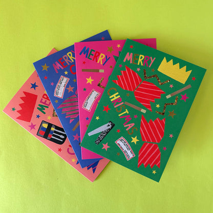 Four colourful Christmas greeting cards fanned out on a bright lime green background. The cards feature festive illustrations including crackers, stars, a paper crown, and the words 'MERRY CHRISTMAS'.