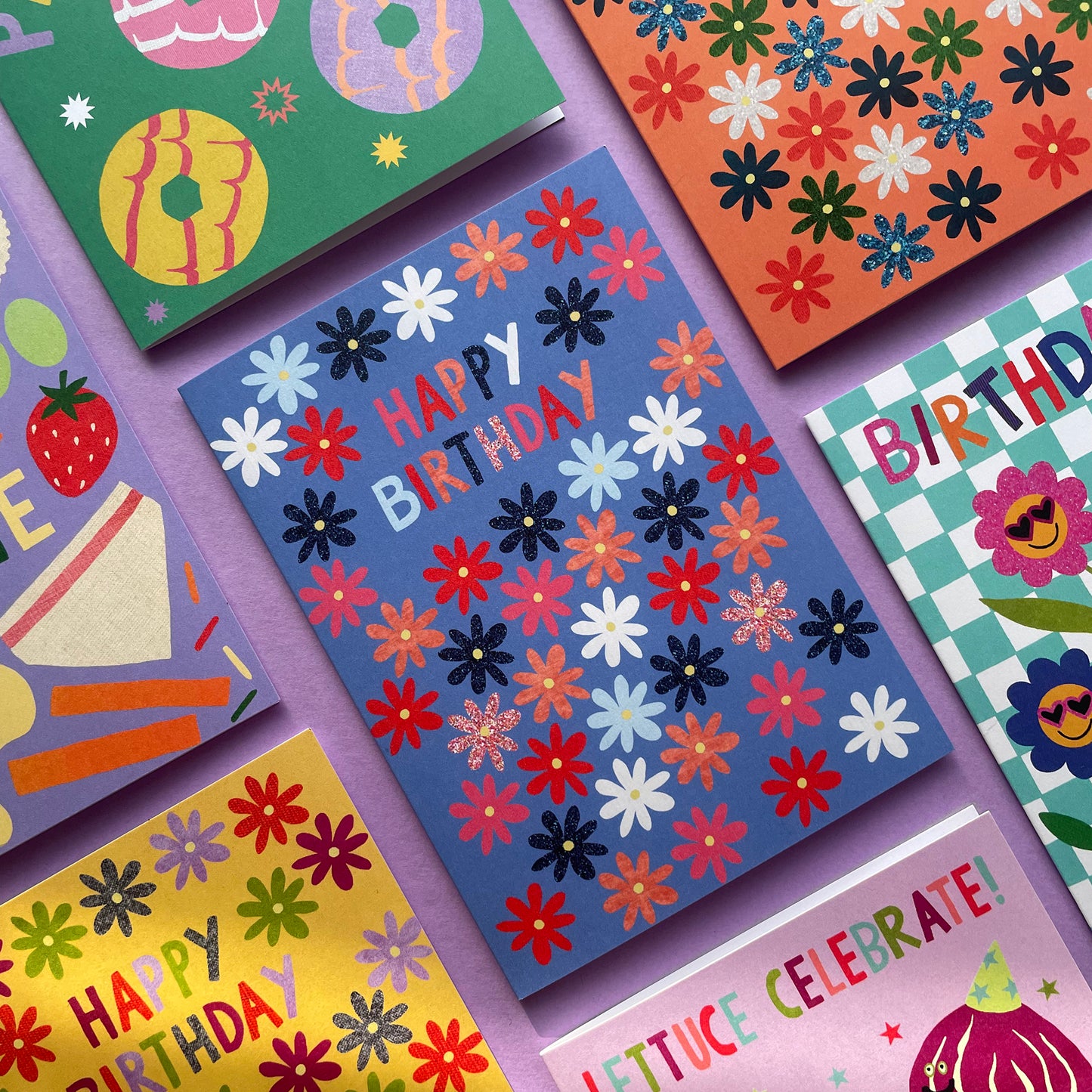 Collection of colourful birthday cards with various designs on a purple background