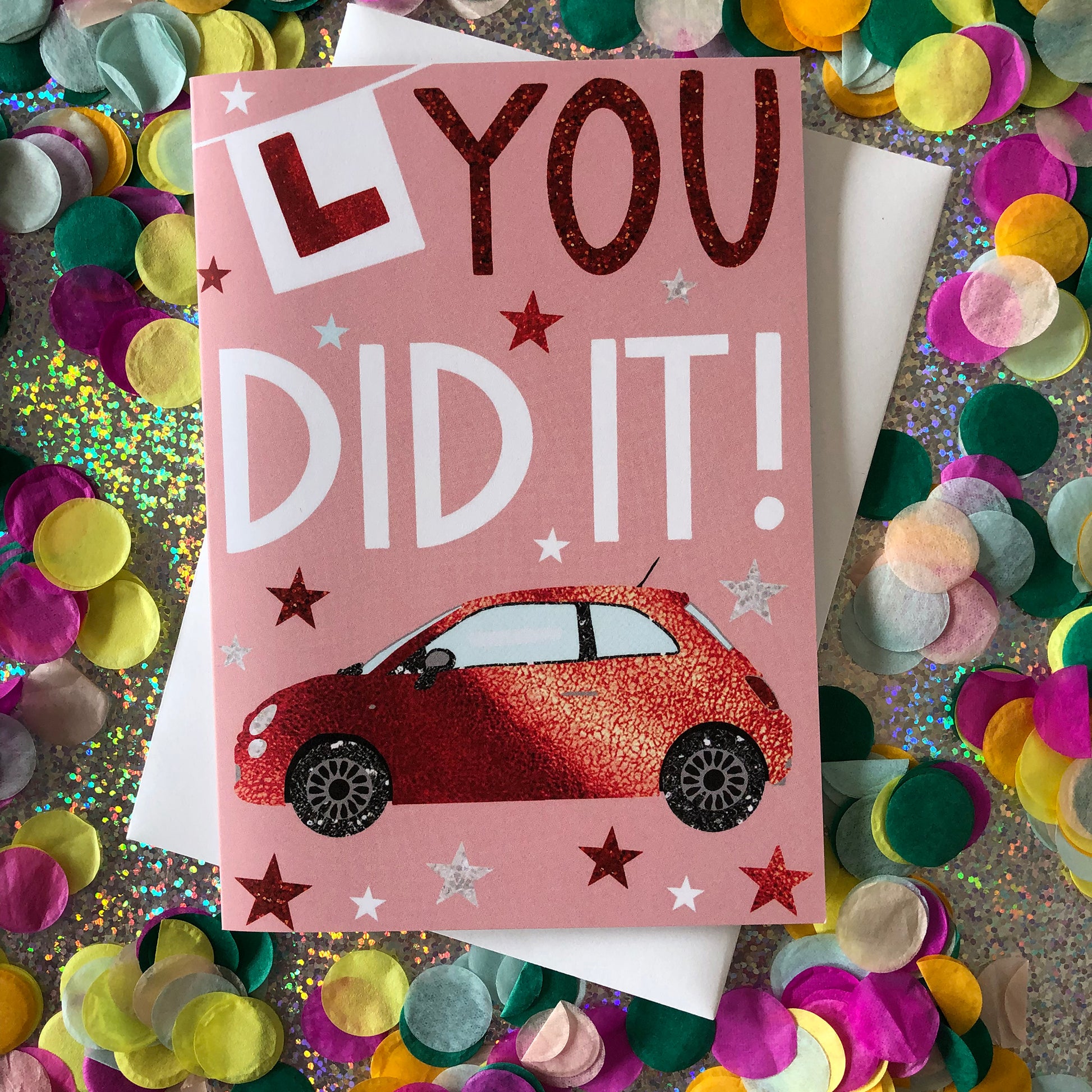 Image shows a pastel pink card with a red sparkly car and L Plate with the words "You Did It!'