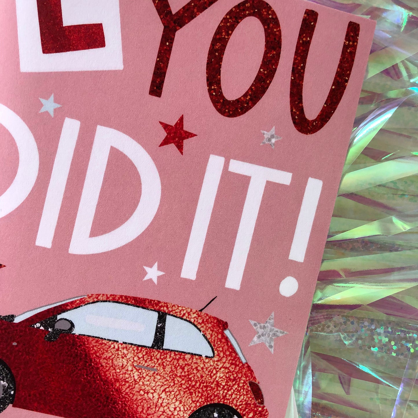 Image shows a pastel pink card with a red sparkly car and L Plate with the words "You Did It!'