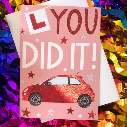 Image shows a pastel pink card with a red sparkly car and L Plate with the words "You Did It!'