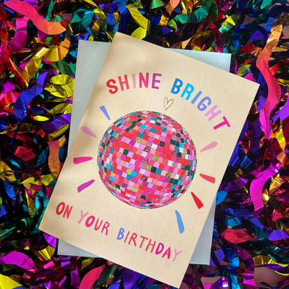 Birthday card with colourful text and disco ball illustration on a confetti background