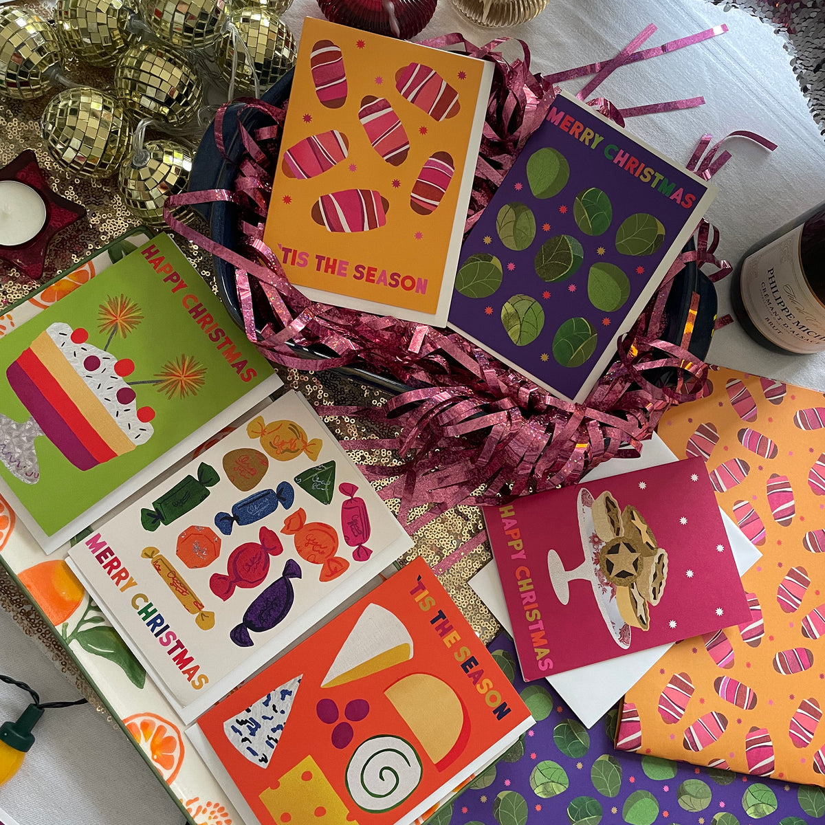 Colourful Christmas cards with festive designs on a table with decorative items.