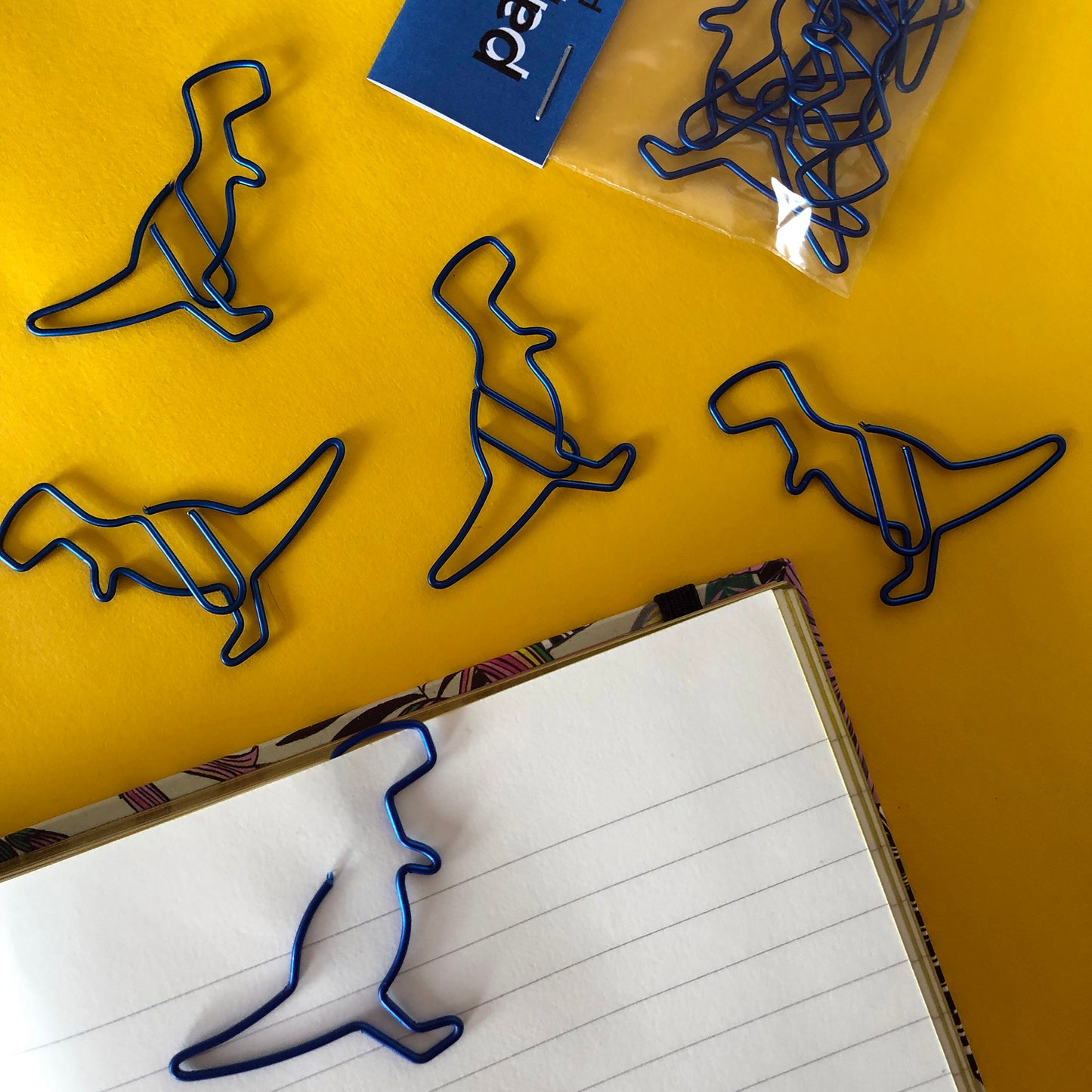 Image shows a set of metallic blue dinosaur shaped paperclips.