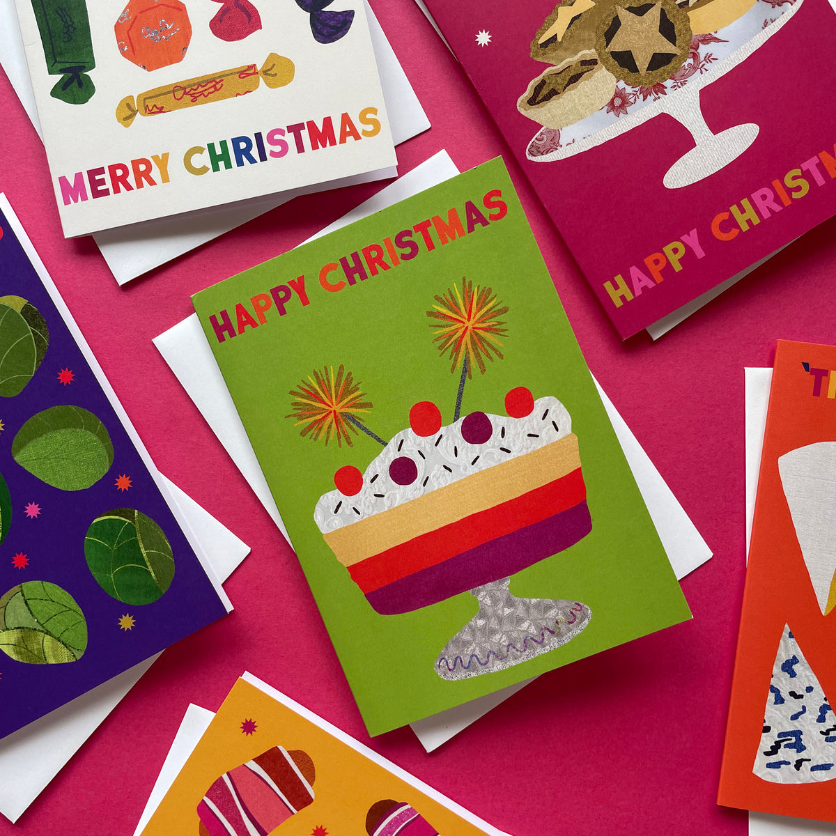 Colourful Christmas cards with various designs on a pink background
