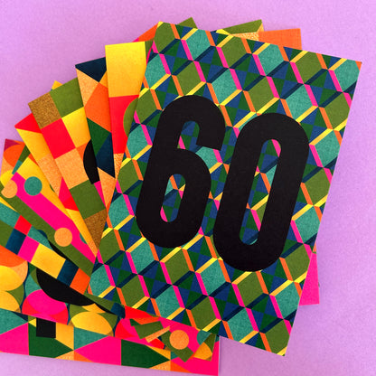 A fanned stack of colorful geometric patterned cards or envelopes on a solid pink background, with the top card featuring a black '60' overlay.