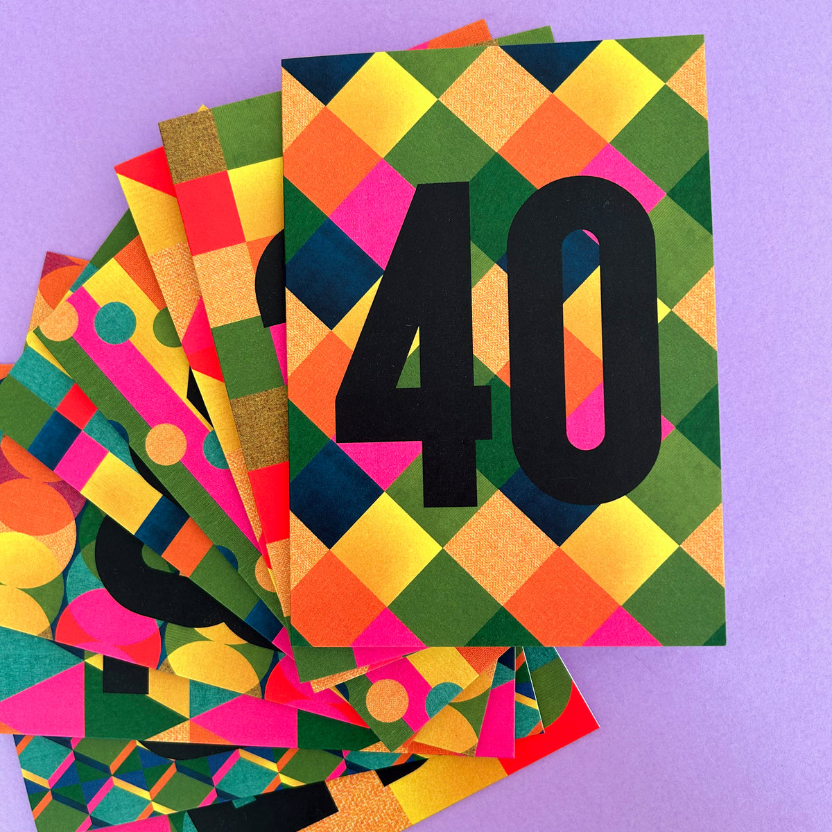 A stack of colourful geometric patterned cards fanned out on a light purple background, with the top card displaying the number 40 in bold black text.