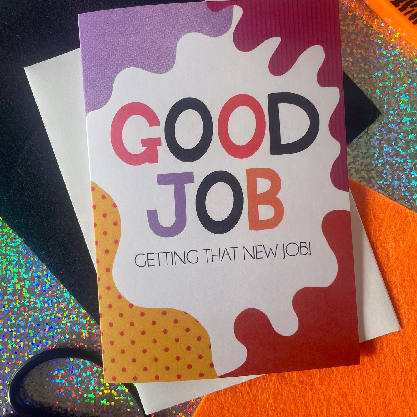 Image shows a bright greetings card with colourful, abstract shapes around the edge and the wording "Good Job getting that new job!"