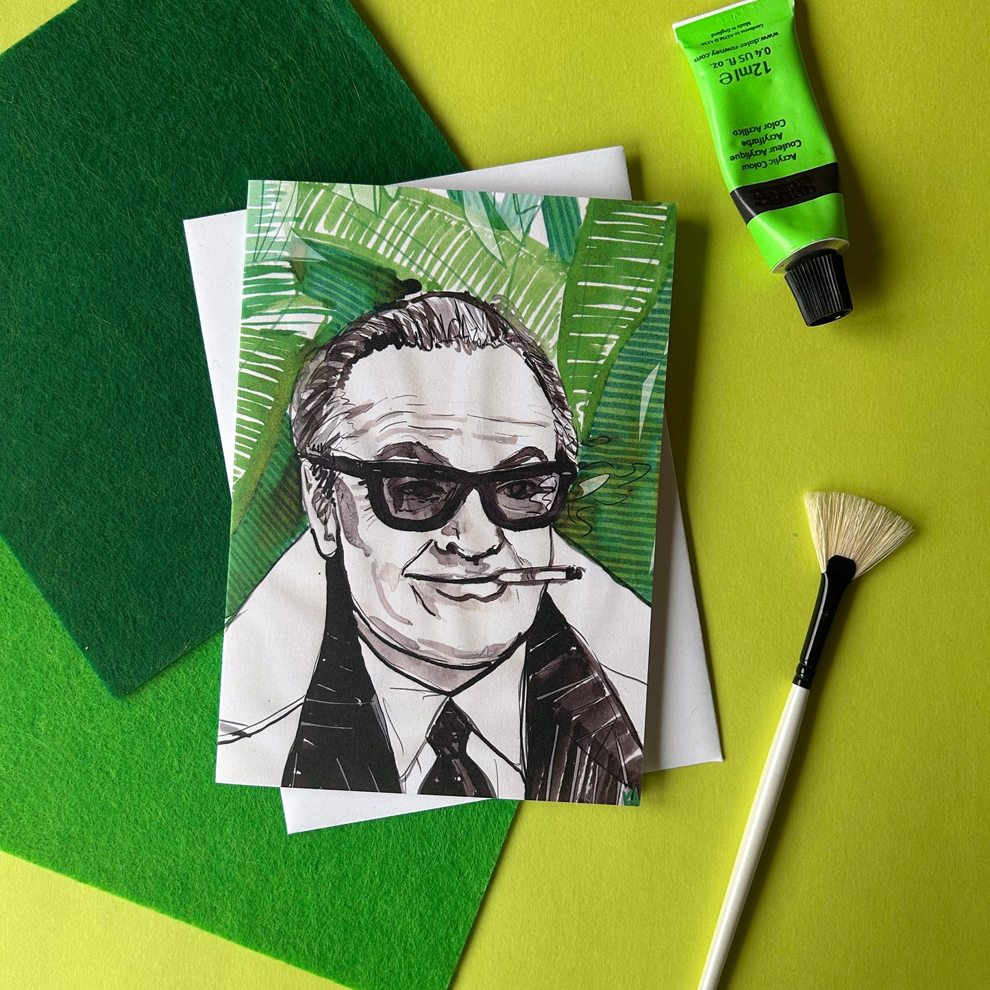 Card with a black and white illustration of a person smoking a cigar, surrounded by green leaves on a green and yellow background.