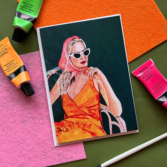 Colorful painting of a woman in an orange dress and pink headscarf on a colorful background with art supplies.