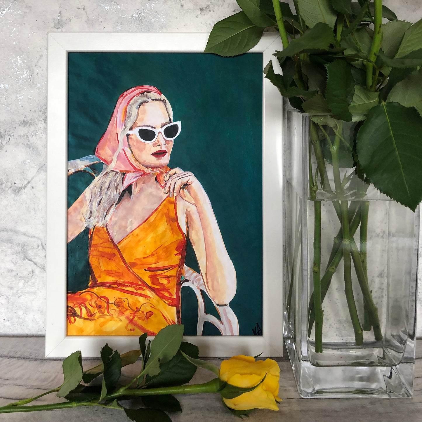 Image of a framed portrait of a woman in an orange dress and pink headscarf. 