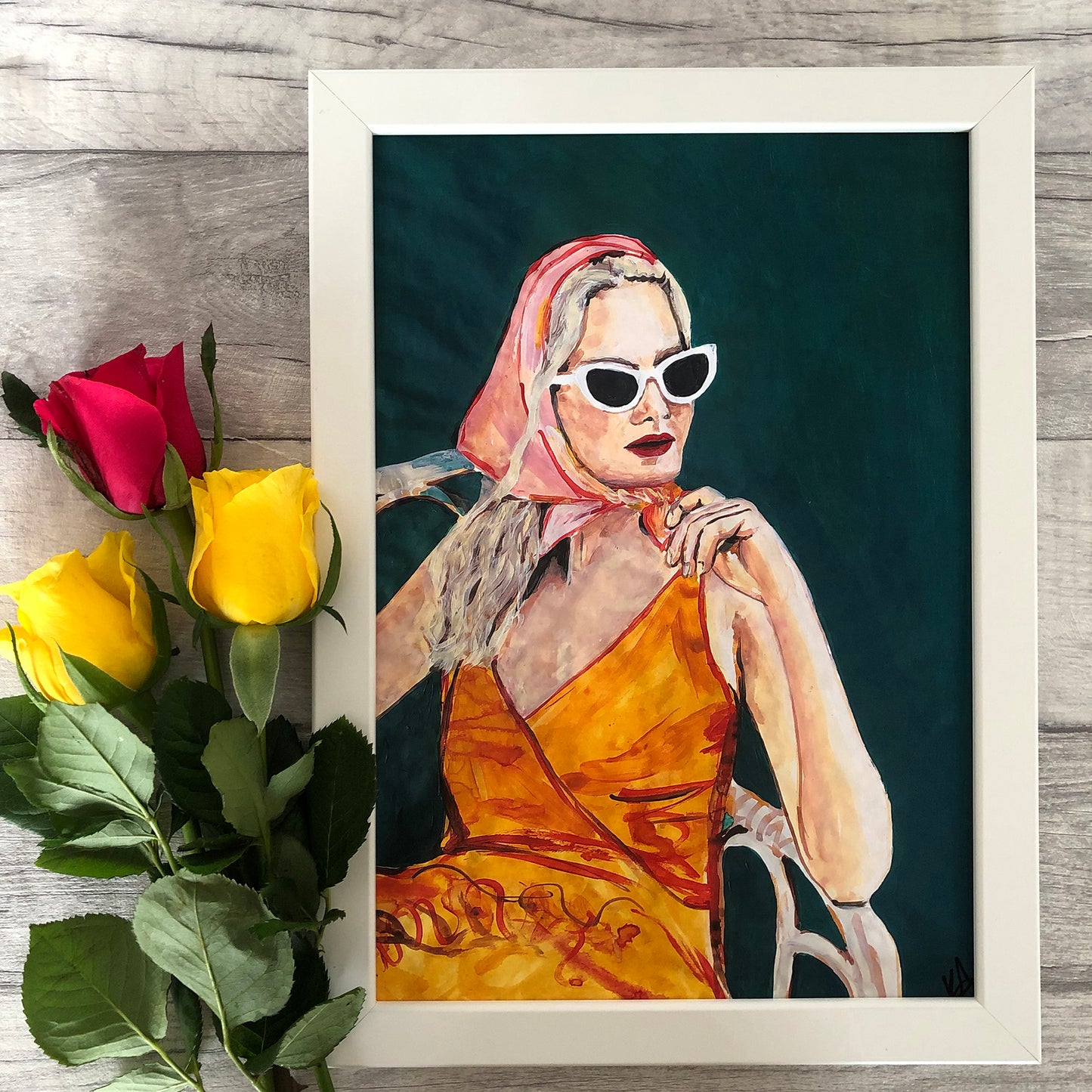 Image of a framed portrait of a woman in an orange dress and pink headscarf. 