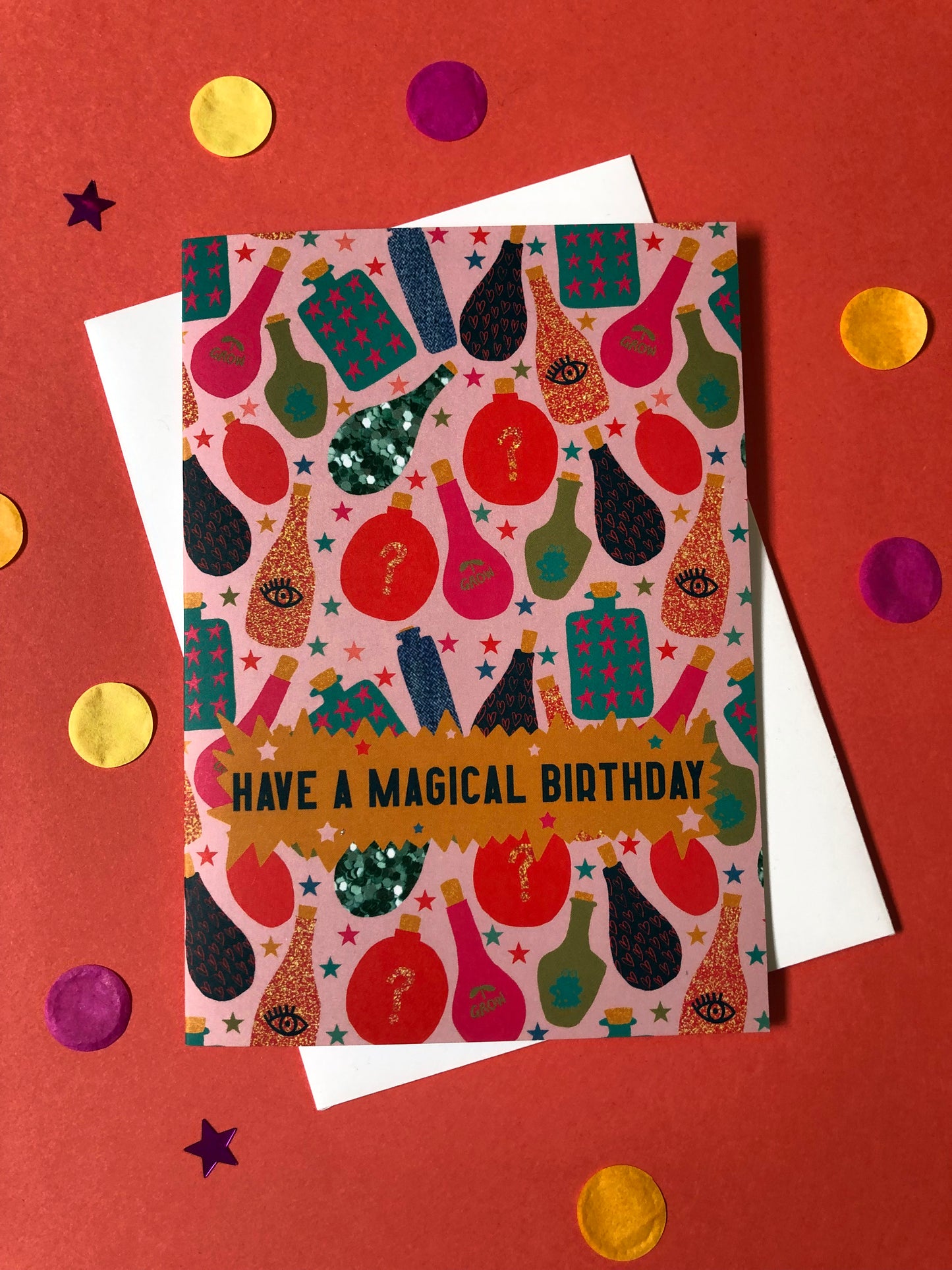 Fun, magical birthday card with colourful magic potion designs on a red background.