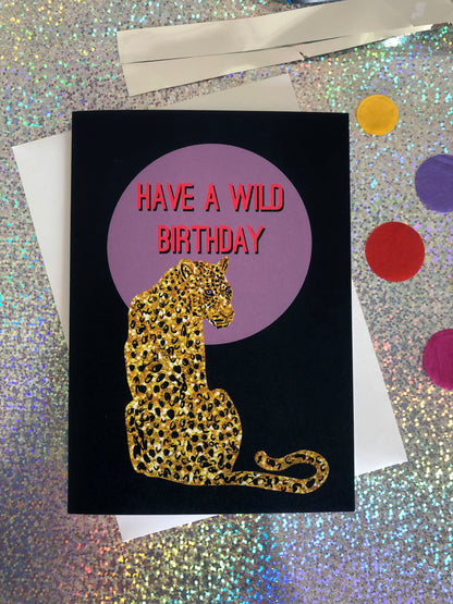 Wild birthday card featuring a gold glitter leopard in front of a lilac full moon.