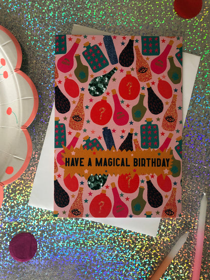 Fun, magical birthday card with colourful magic potion designs on a holographic background.