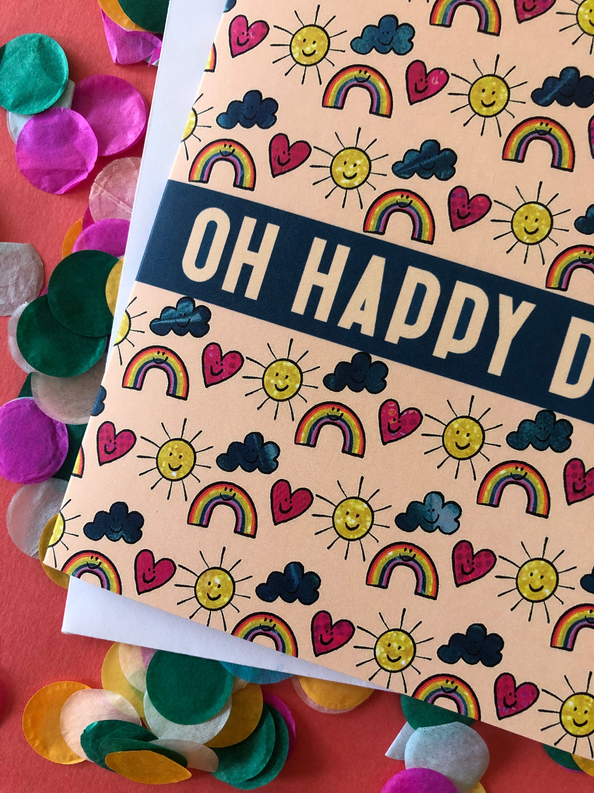 Everyday greetings card that says 'oh happy day' and features a fun pattern of suns, clouds and rainbows