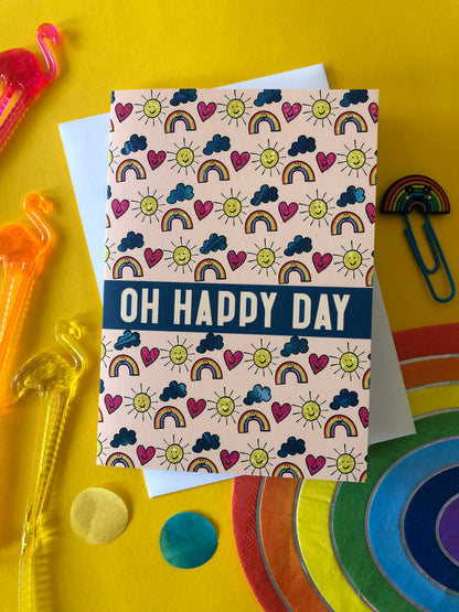 Everyday greetings card that says 'oh happy day' and features a fun pattern of suns, clouds and rainbows
