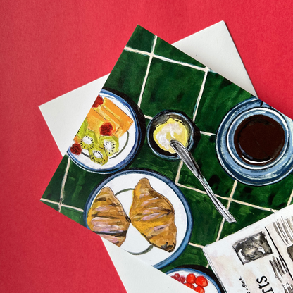 Illustration of a breakfast scene with croissants, coffee, and fruit on a green table.
