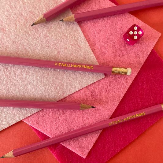 Image shows a pink pencil with gold lettering that says #itsallhappening 