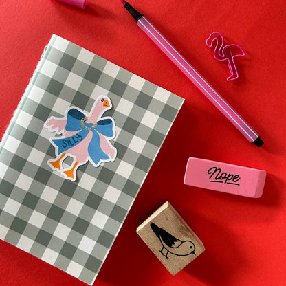 Checkered notebook with sticker, pink pen, and rubber on red background