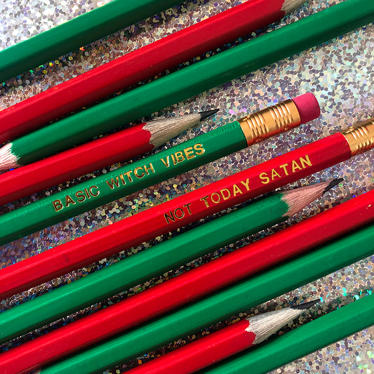 Image of a collection of pencils in bright red and green The red pencils are embossed in gold with 'not today satan' and the green ones are embossed in gold lettering with 'basic witch vibes'