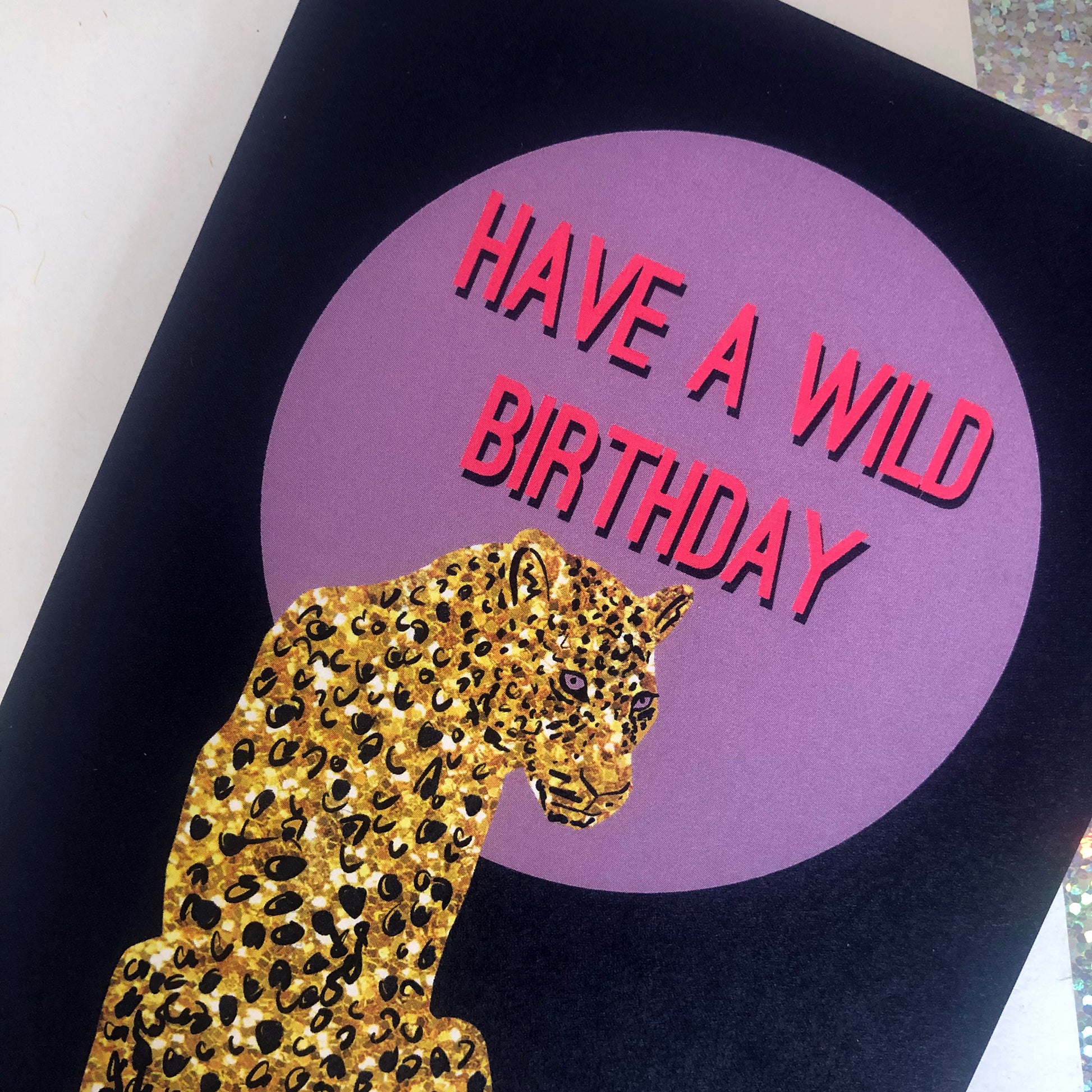 Wild birthday card featuring a gold glitter leopard in front of a lilac full moon.