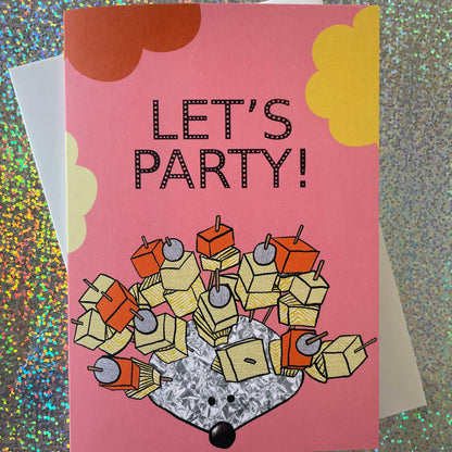 Image shows a pink greetings card with an illustration of a silver foil 'party hedgehog' with cheese, pineapple and pickled onions on cocktail sticks and the words 'let's party'