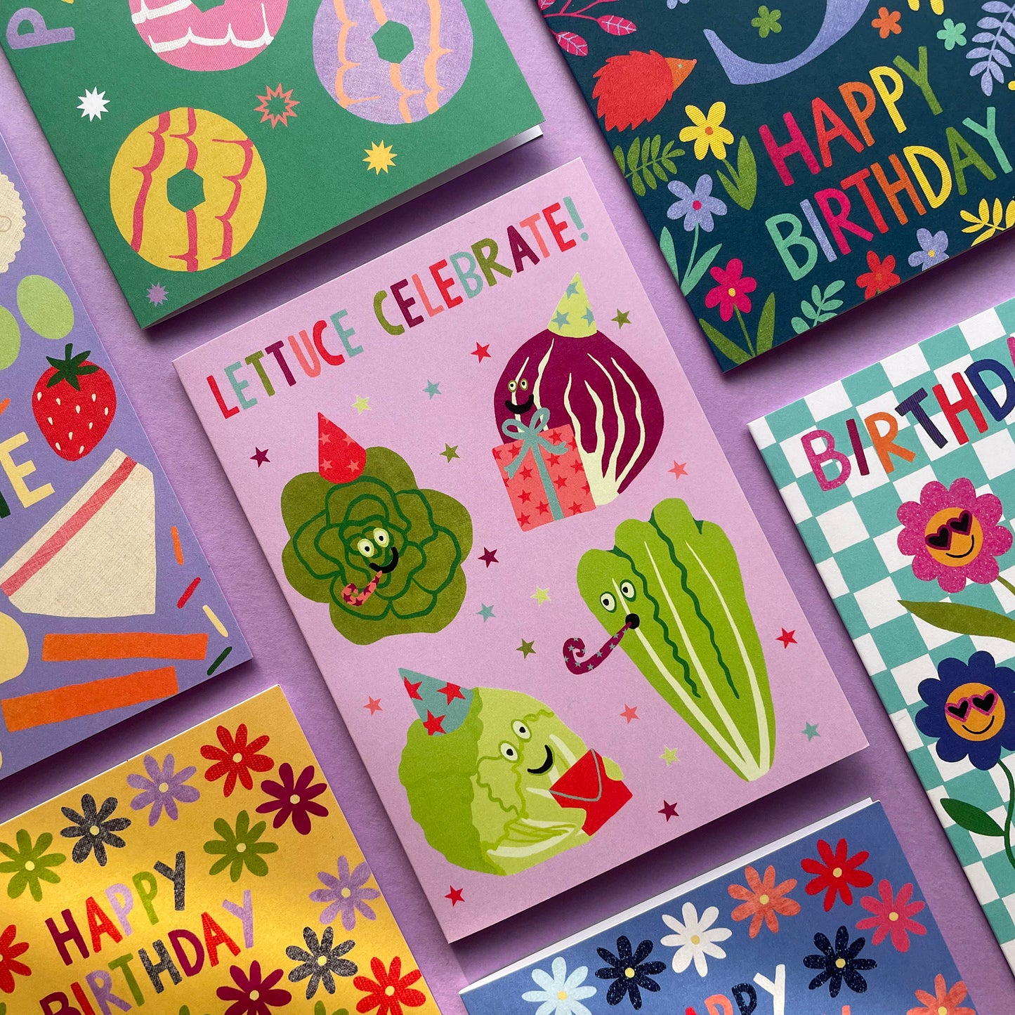 Collection of colorful greeting cards with various designs on a purple background