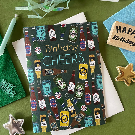 Image shows a birthday card with the greeting 'Birthday Cheers' and a pattern made of collaged beer bottles and cans.