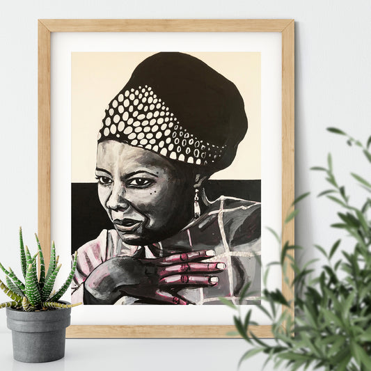 Image shows a framed black and white portrait of Maya Angelou. Artwork is painted in black and white wirth a pink undertone visible in the hand and shoulder