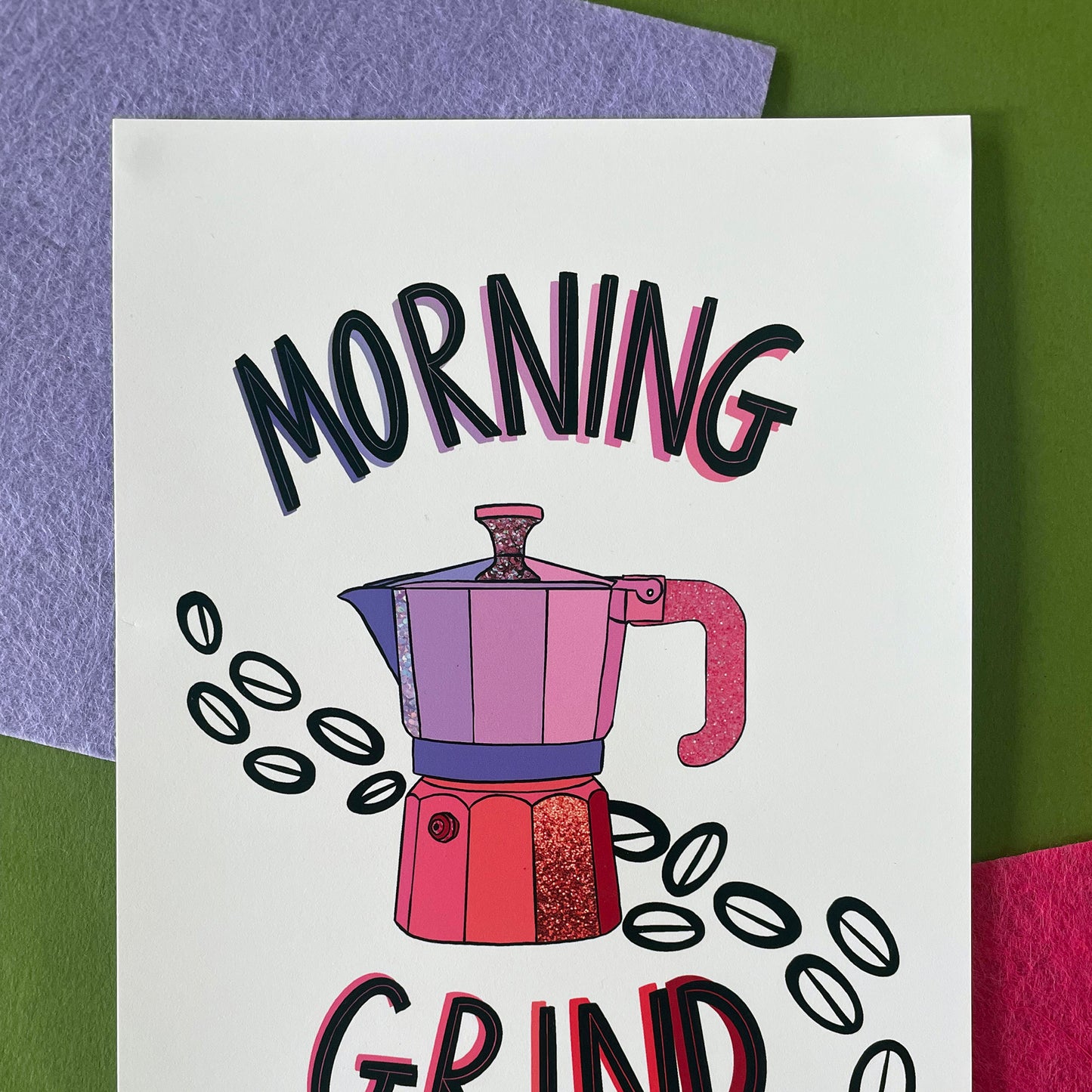 Image shows an lllustration of a stovetop espresso maker in shades of pink and purple with ink drawn coffee beans behind it. Modern graphic lettering reads Morning Grind. 