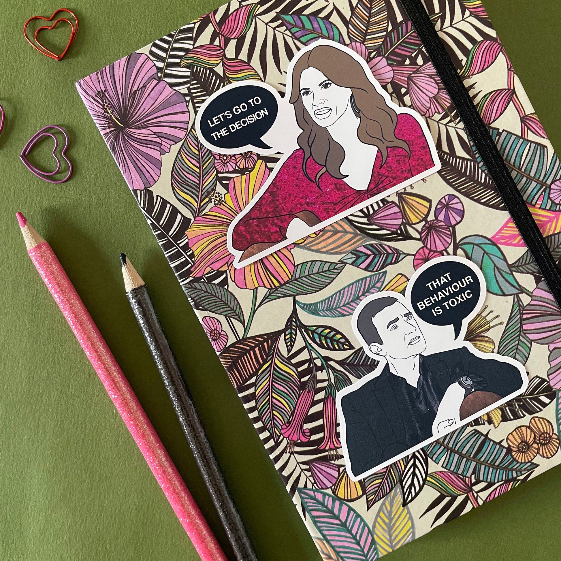 Image of a notebook with 2 illustrated stickers featuring experts Alessandra and John from Married at First Sight Australia