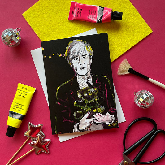 Black card with a colourful illustration of Andy Warhol at studio 54, surrounded by art supplies on a pink background.
