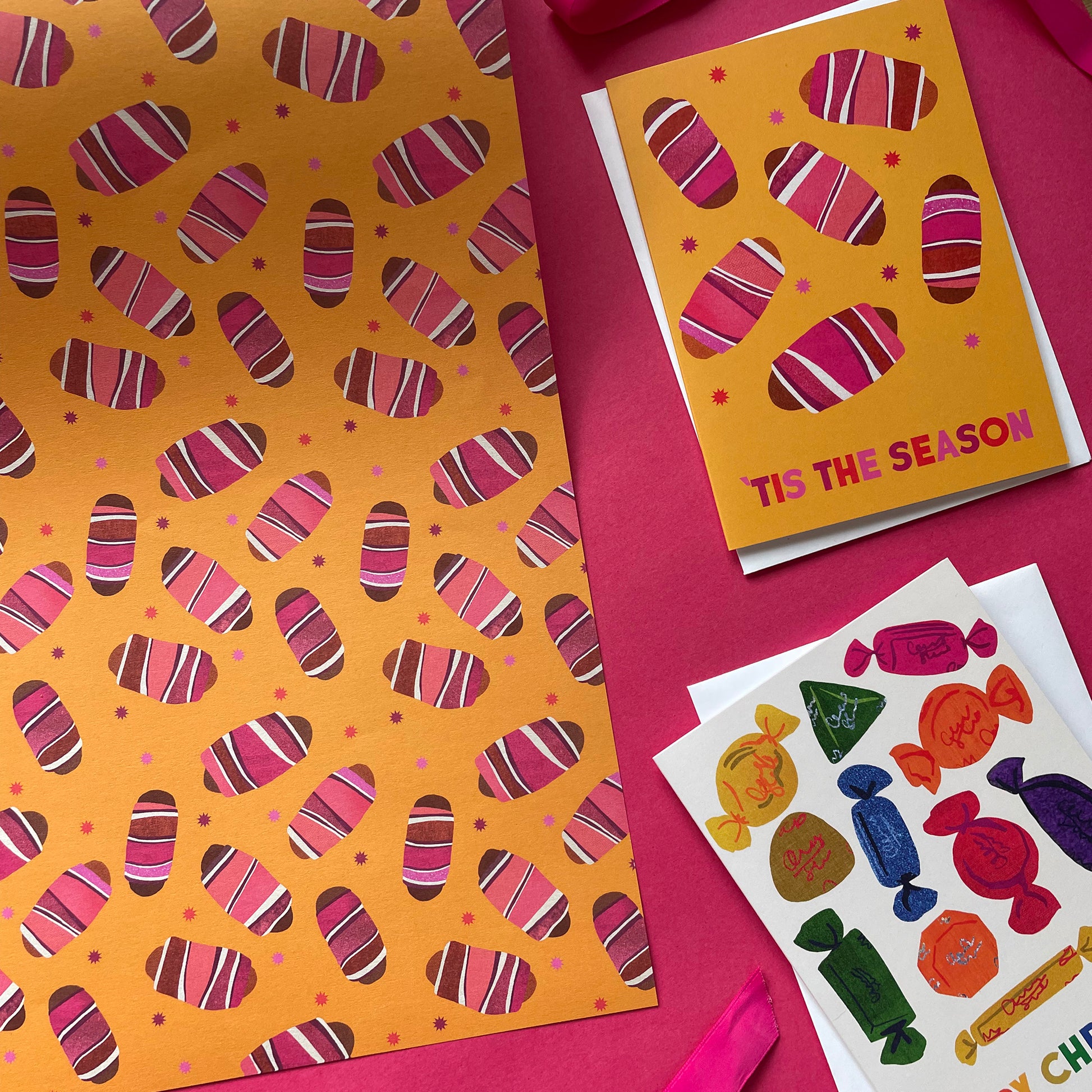 Decorative paper with pigs in blankets pattern on a mustard background with tiny colourful stars.