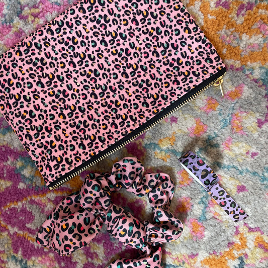 Image shows a useful zip pouch in a pretty pink colour with a leopard print pattern with pops of neon.