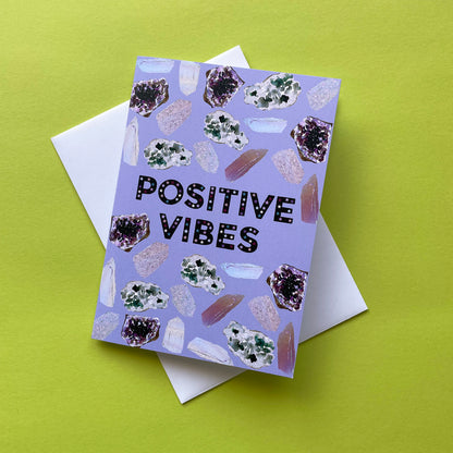 Image of a lavender coloured greetings card with illustrations of crystals and the words 'Positive Vibes'