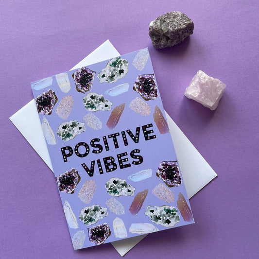 Image of a lavender coloured greetings card with illustrations of crystals and the words 'Positive Vibes'
