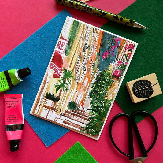 Card with artistic design of a colourful Provencal street with stationery items.