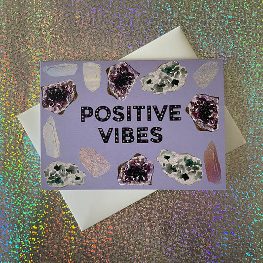 Image of a lavender coloured greetings card with illustrations of crystals and the words 'Positive Vibes'