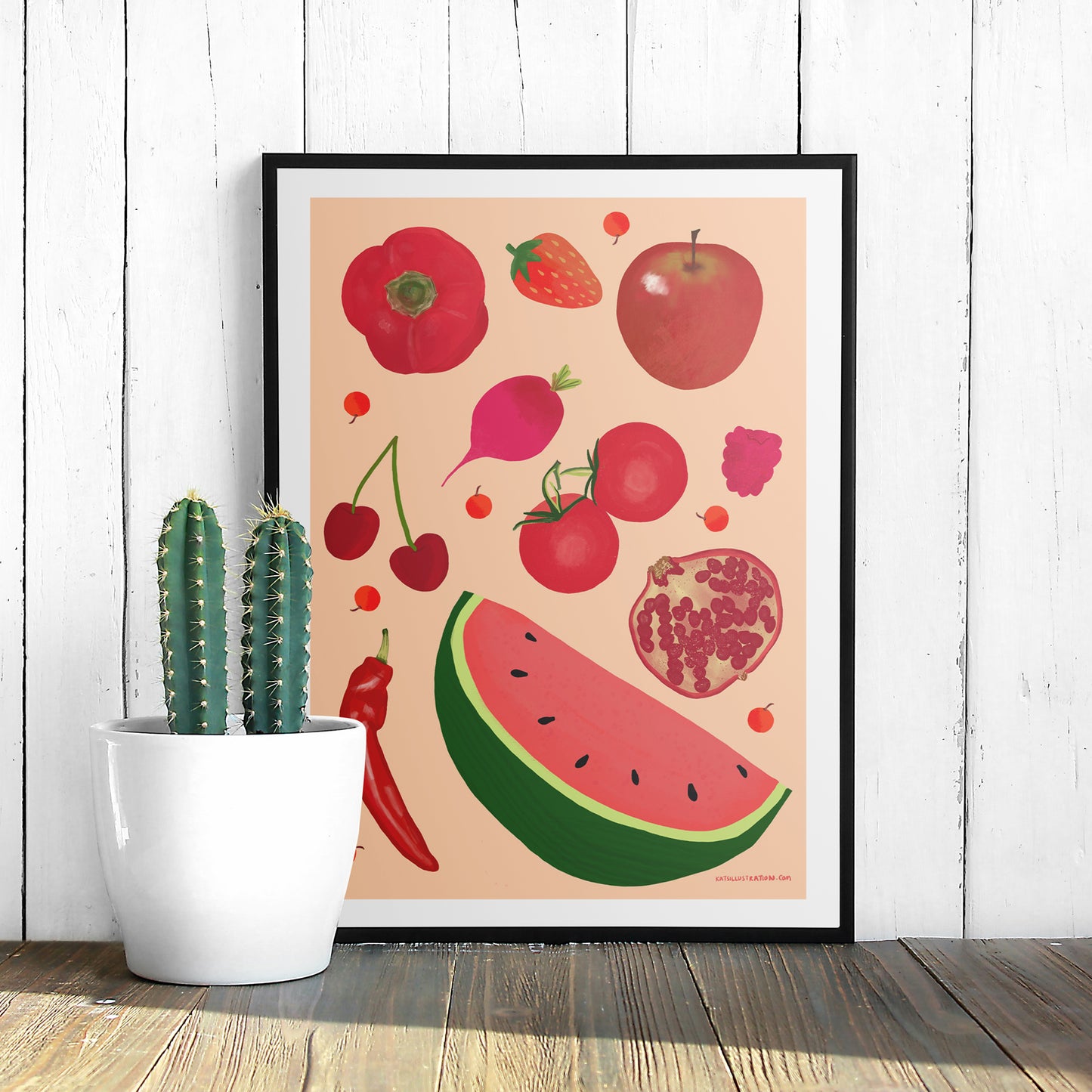 Image of a framed art print of red fruit and vegetables on a peach background.