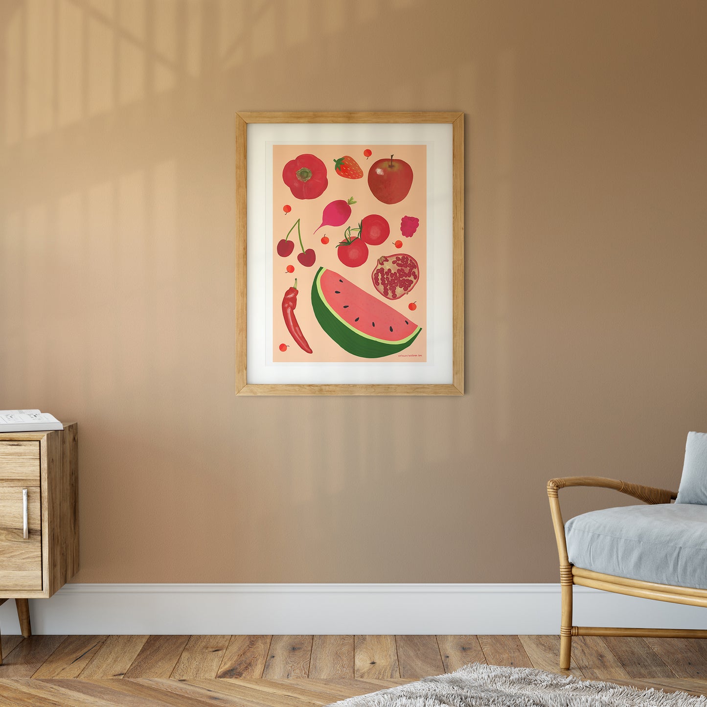 Image of a framed art print of red fruit and vegetables on a peach background.