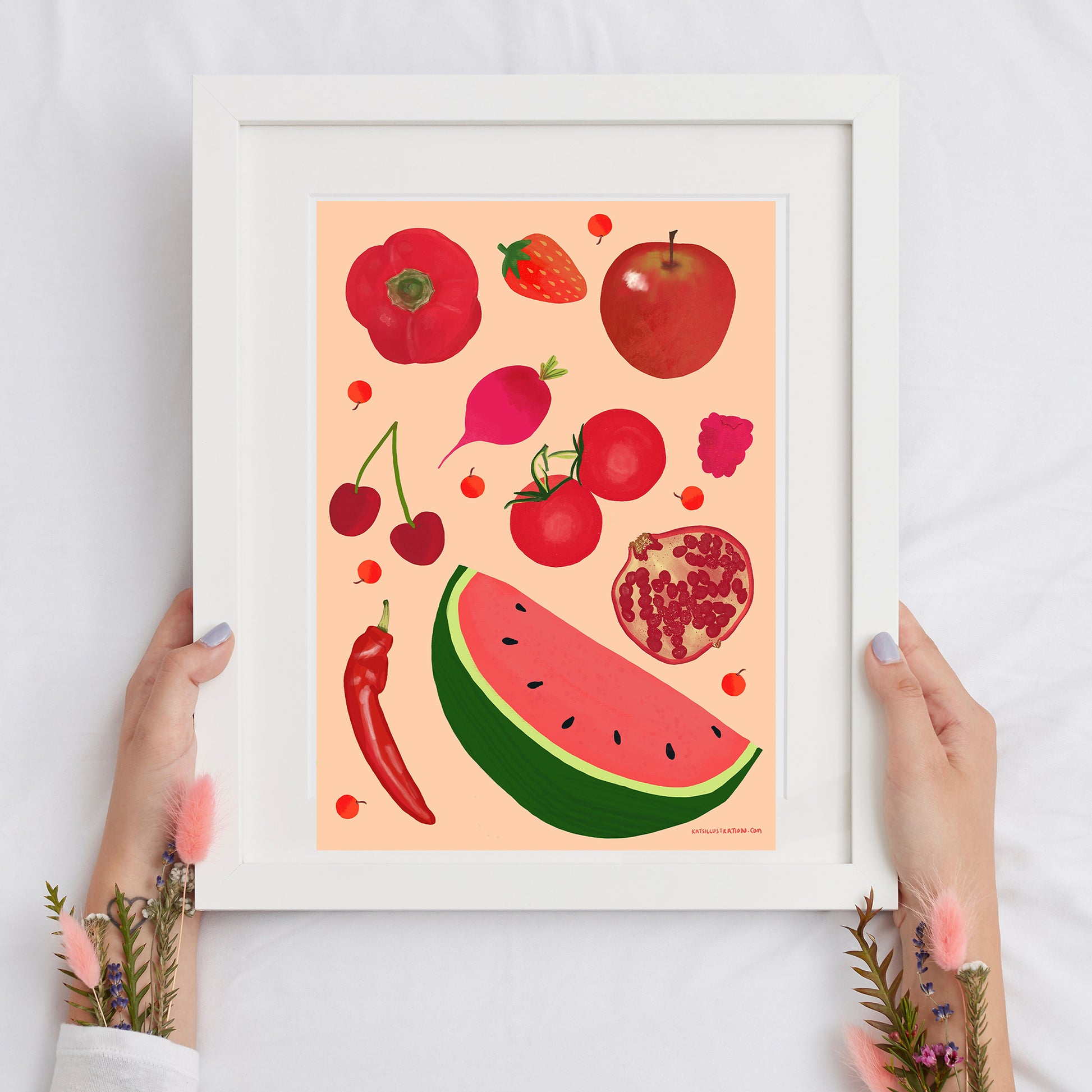 Image of a framed art print of red fruit and vegetables on a peach background.