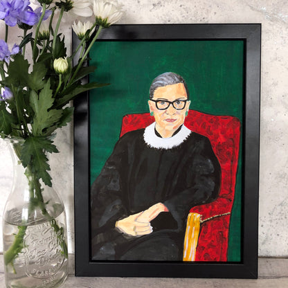 Image of a framed art print of a portrait of Ruth Bader Ginsburg sitting on a red chair with a green background, originally painted in acrylics 