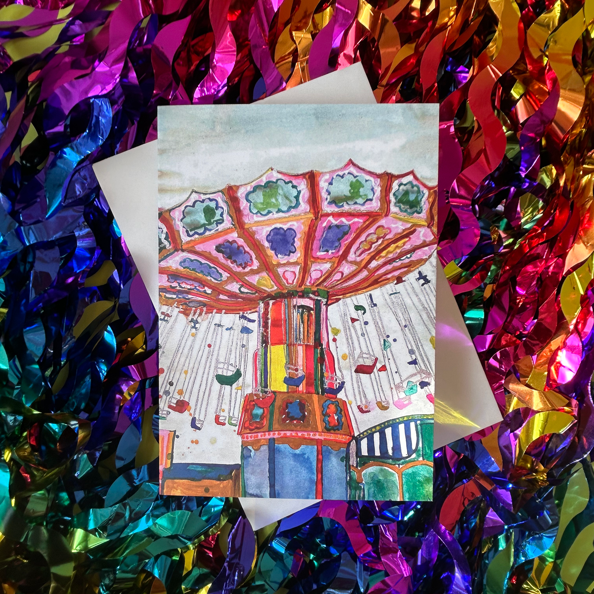 Greeting card with a colourful carousel design on a rainbow metallic tinsel background