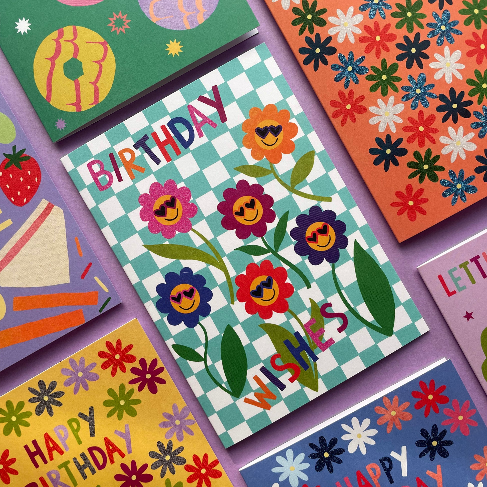Colorful birthday cards with floral designs and text on a purple background