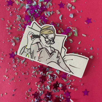 Sticker of Sonja from RHONY watching TV in bed wearing a tiaraon a pink background with star-shaped confetti