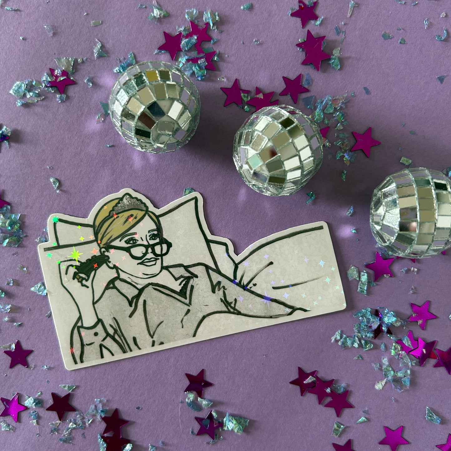 Sticker of Sonja from RHONY watching TV in bed wearing a tiara on a purple background with disco balls and star-shaped confetti.