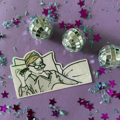 Sticker of Sonja from RHONY watching TV in bed wearing a tiara on a purple background with disco balls and star-shaped confetti.