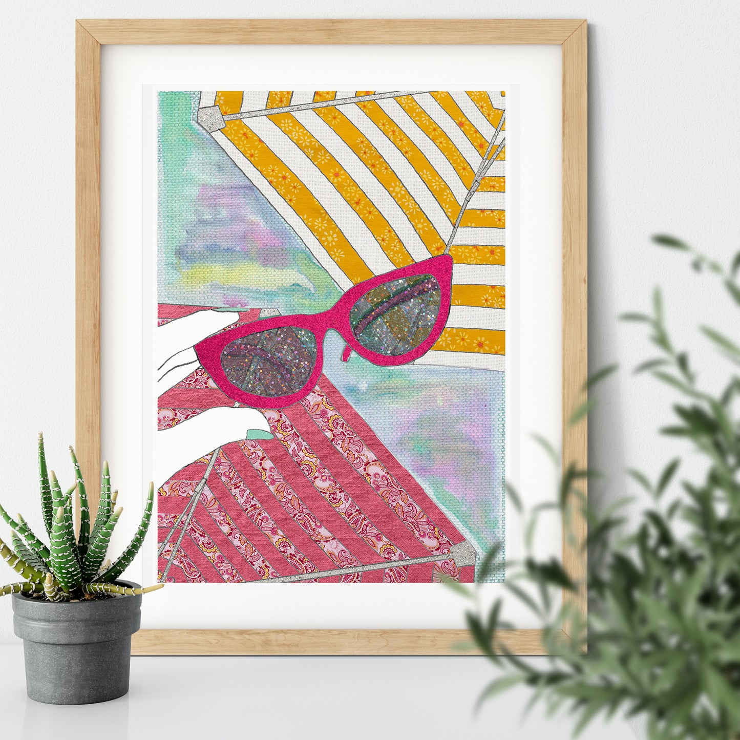 Framed illustration of the sunlight shining through a pair of pink sunglasses on a white wall with plants