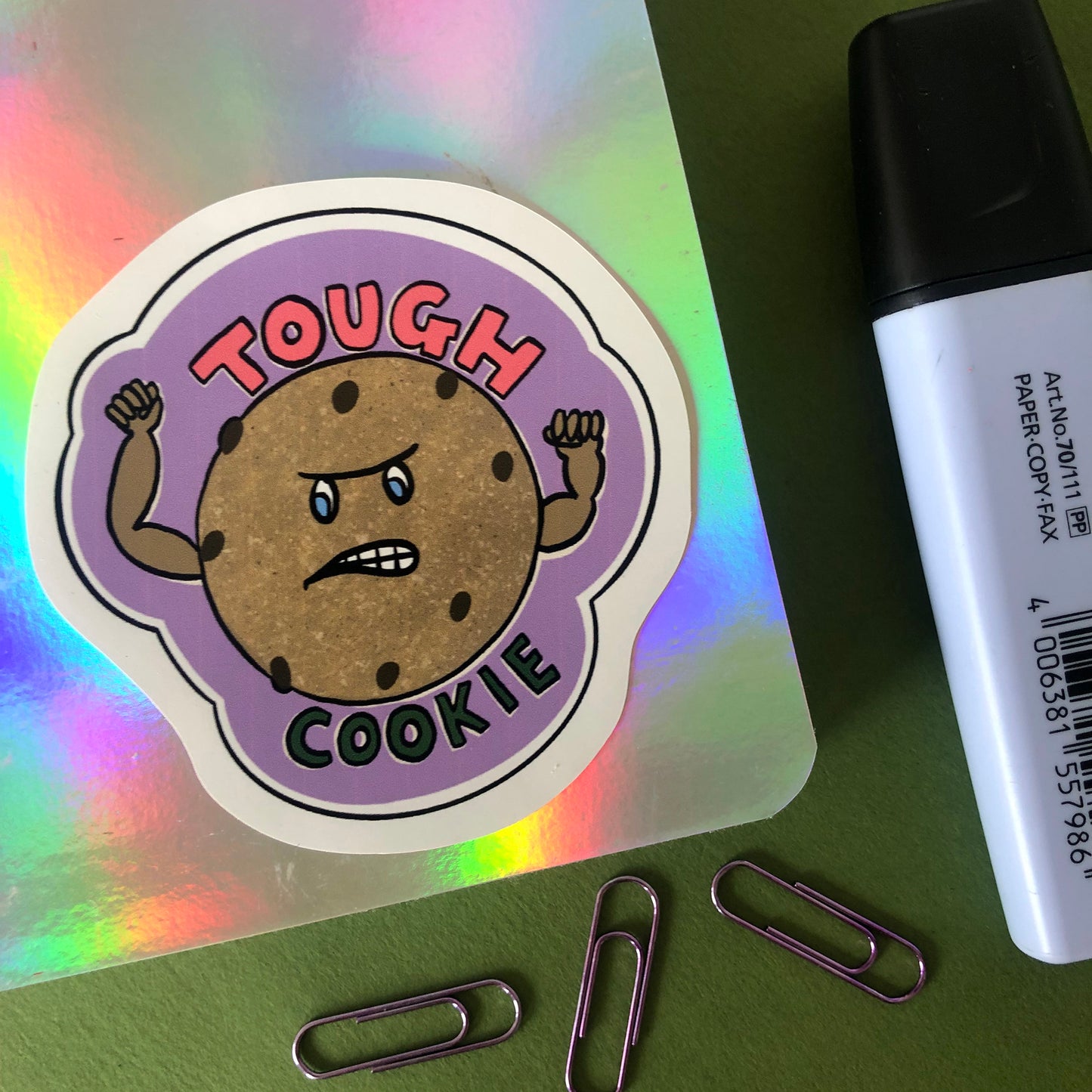 Image shows a vinyl sticker featuring an illustration of a cookie with muscles and the wording 'Tough Cookie'